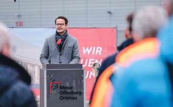 Mann in Mantel steht vor Podium 