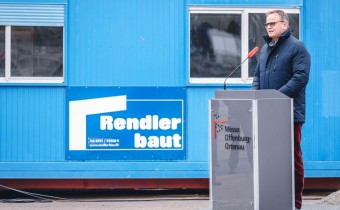 Mann in Mantel steht vor Podium 