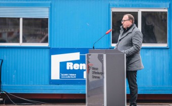 Mann in Mantel steht vor Podium 